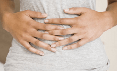 A woman with a stomachache holding her stomach.