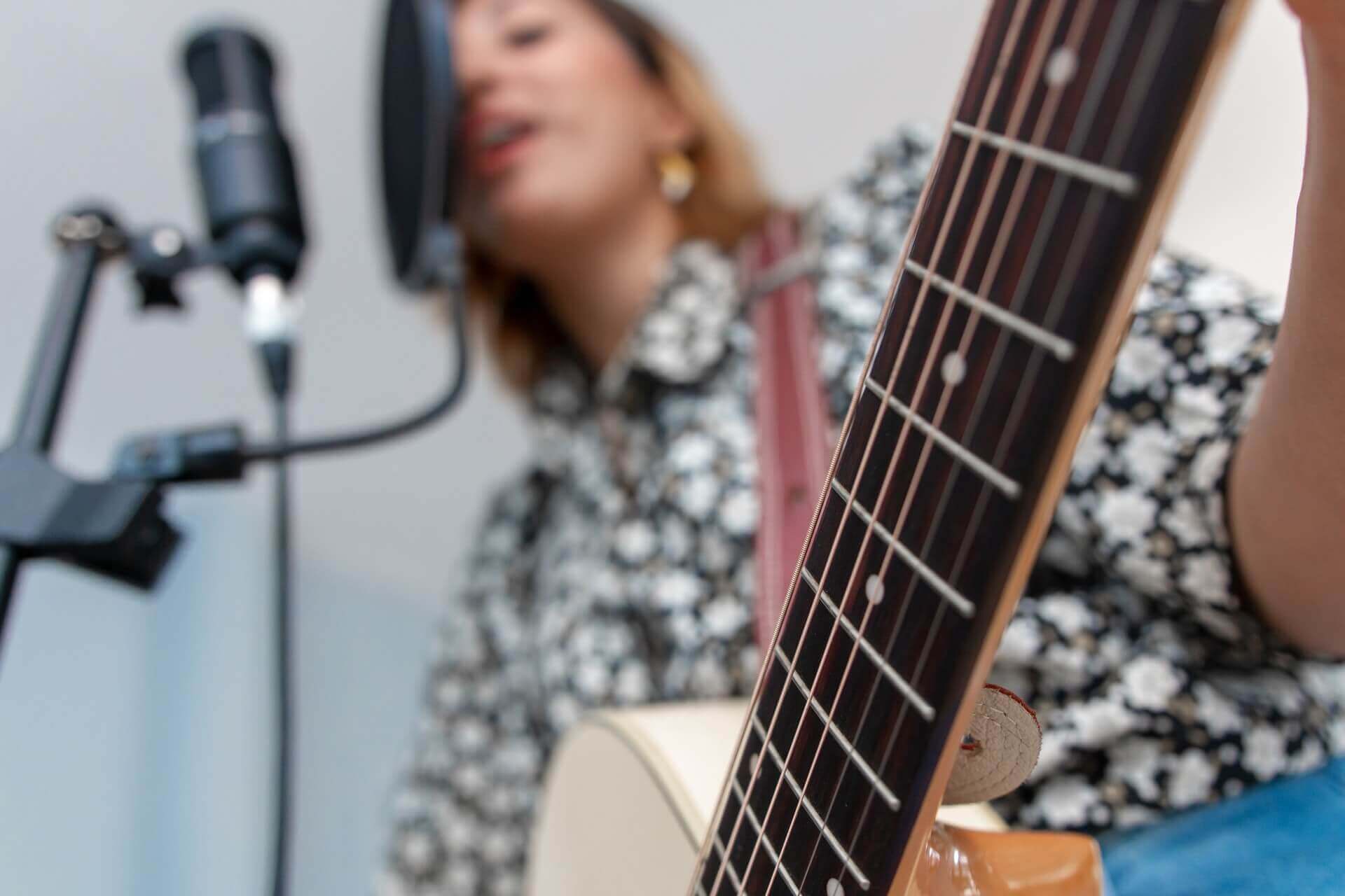 woman singing and playing guitar low angle shot