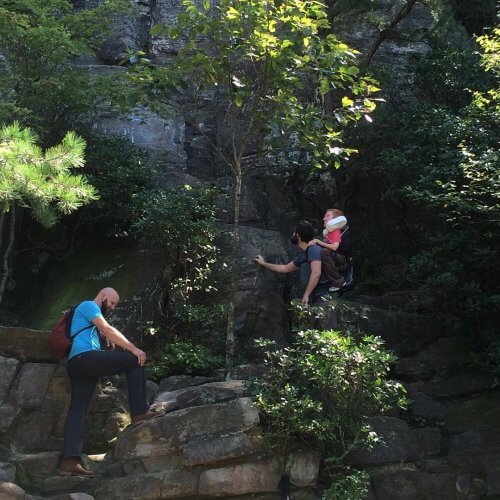 Kevan climbing a mountain on the back of one of his friends