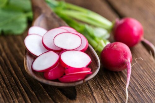 Some sliced radishes in a wooden spoon.