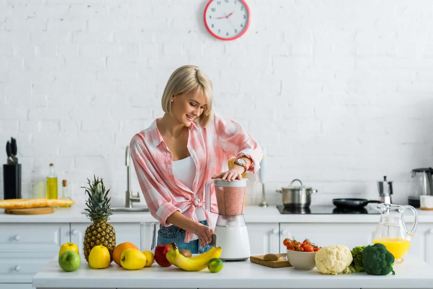 A woman preparing fruit smoothies in her kitchen.