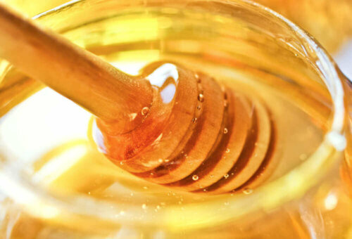 A honey dipper in some honey.