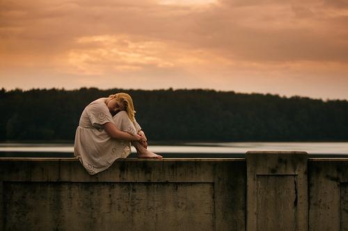 A silent girl sitting on a wall in nature