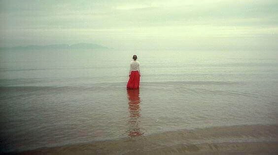 Woman in a red skirt standing by the ocean