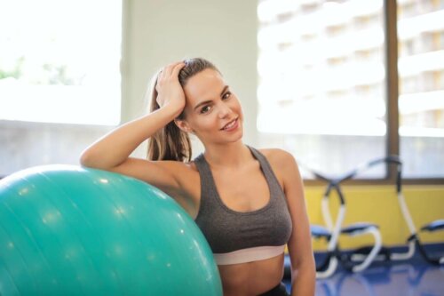 A woman leaning against an exercise ball.