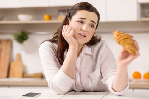 A woman sad that she can't eat a croissant because it'll weaken her bones.