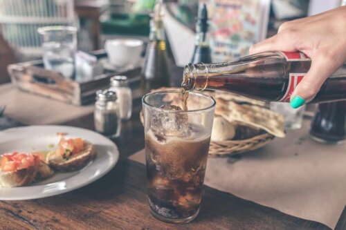 restaurant pouring a soda into a glass with ice at a meal