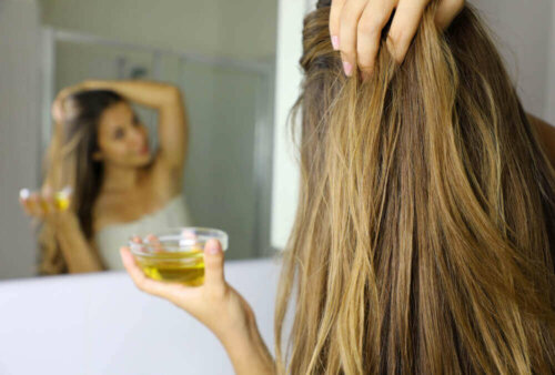 woman applhing oil to her hair looking in a mirror