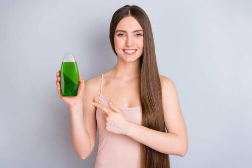 woman smiling pointing to a shampoo bottle