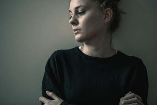 A sad woman leaning against a wall.