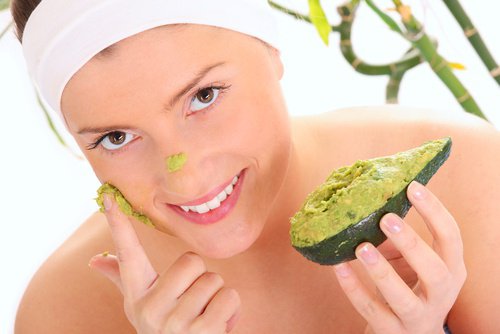 Woman applying mashed avocado to face as treatment