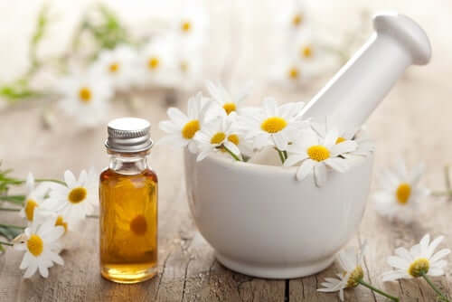 Some chamomile oil beside a mortar and pestol.