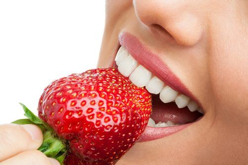A woman eating a strawberry.
