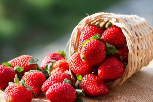 Small basket full of small strawberries green in background arterial health