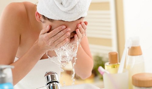 Woman rinsing face with water clean face with natural oils