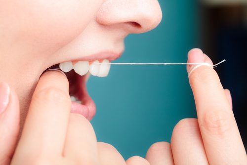 A woman flossing her teeth.