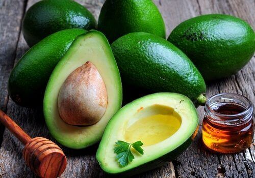 Avocado seed and whole avocado on table with honey jar