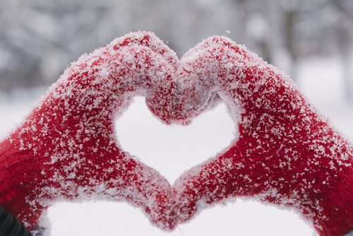 person wearing gloves, making a heart with their hands