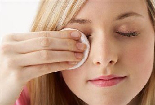 Woman using cotton pad to remove makeup from face with natural oils