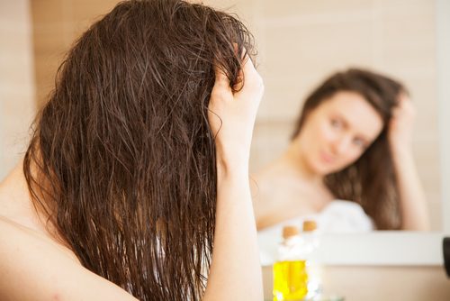 A woman using olive oil on her hair.