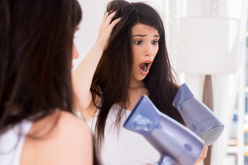 A shocked woman using a hairdryer.
