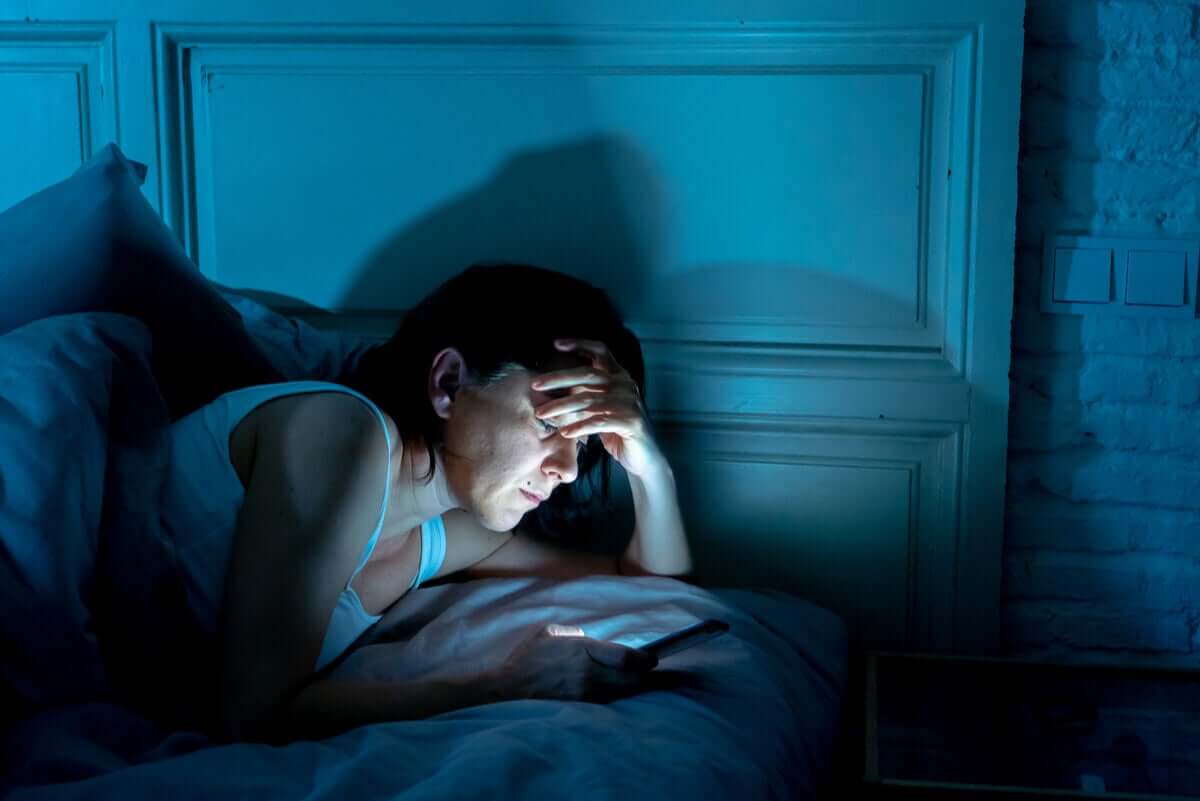 A woman looking at her phone at night.