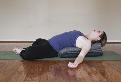 A woman doing the supta buddha pose.
