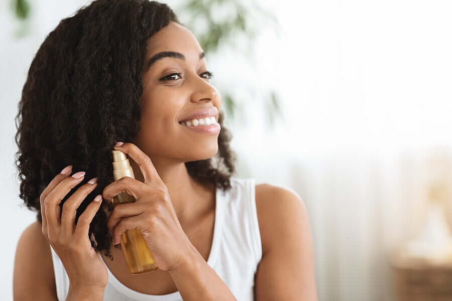 A black woman applying spray to her curls.