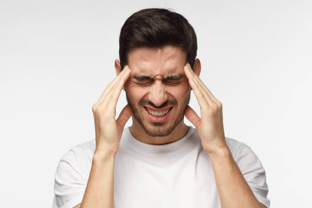 A man with a headache presses his temples.