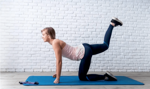A woman doing back leg lifts.