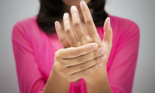 A woman massaging her hand because of tingling skin.