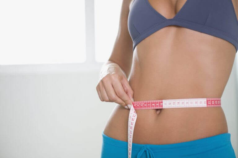 Woman measuring her slim waistline