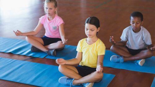 Three children practicing mindfulness during yoga mindfulness for children