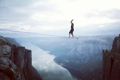 Woman walking on tightrope over mountains