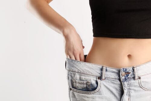 Person wearing old, baggy pants to show improvement of waistline