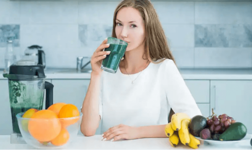 A woman drinking green shakes.