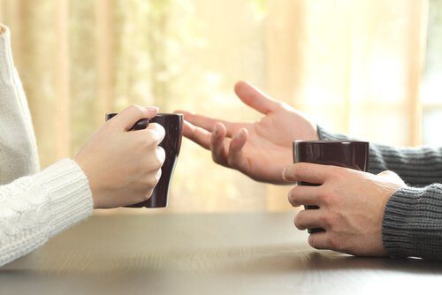 two people holding coffee cups and using body language