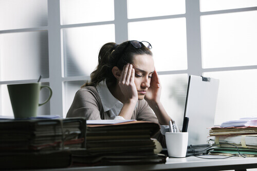 woman with stress headache in front of a computer at work