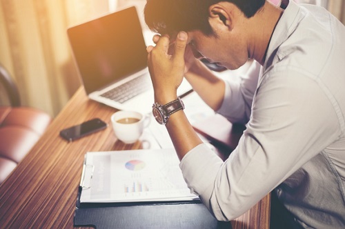 young man with headache at his desk in an office