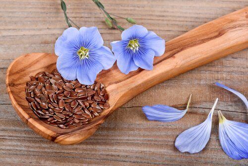 Flaxseeds in a wooden spoon with purple flowers as decoration edible seeds