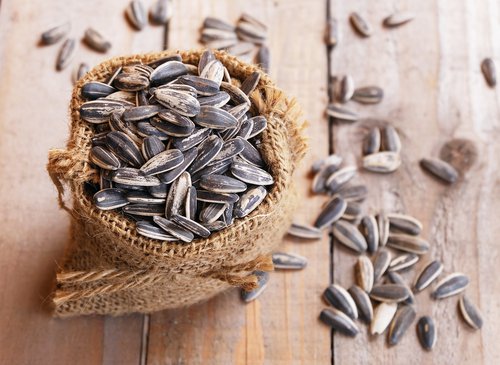 Edible seeds sunflower seeds in a small burlap bag on a wooden surface