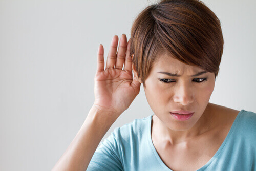 woman with short hair holding her hand to her ear