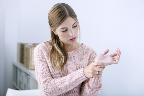 woman wearing a pink sweater with wrist pain