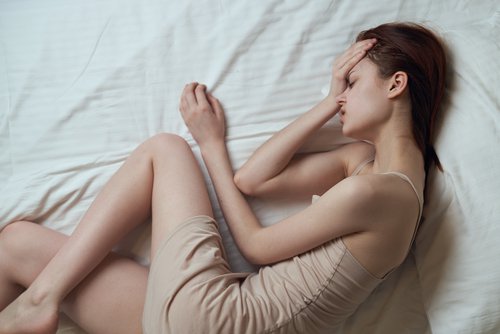 woman laying in bed suffering from menstrual pain