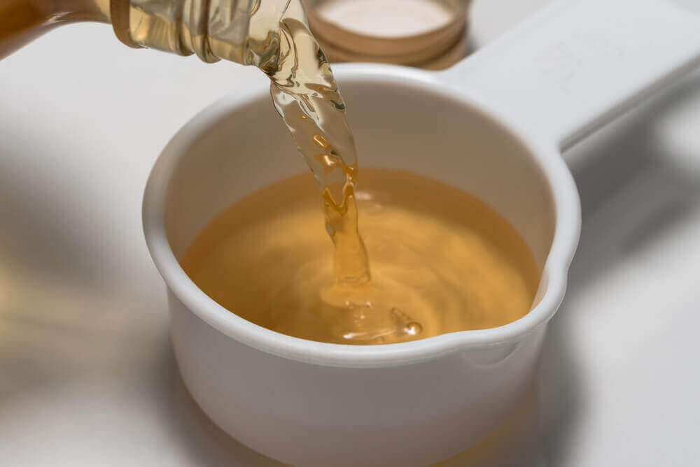 A person pouring vinegar into a cup.