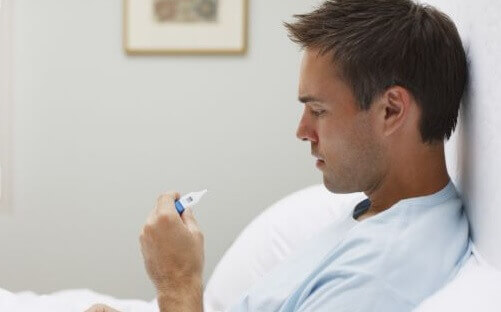 man taking his body temperature with a thermometer