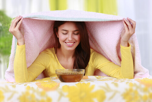 Woman with a steam bath and pink towel to clear her sinuses.