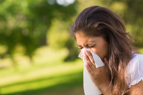 A woman sneezing due to her allergies.