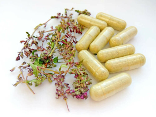 capsules of medicinal plants medication on a table next to flowers