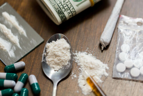various drugs on a wooden surface, powders, pills, and joints